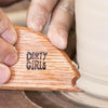 A wood potter's rib with a curved arc, straight edge, and unique V- and U-shaped notches for shaping clay. Amaranth Stoneware Canada.