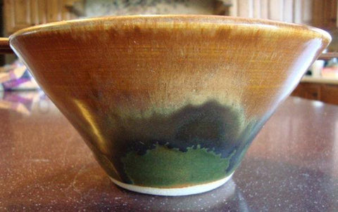 A golden cream glaze with reddish brown streaks. Can show blue crystals and varies widely in color and finish. Amaranth Stoneware Canada.